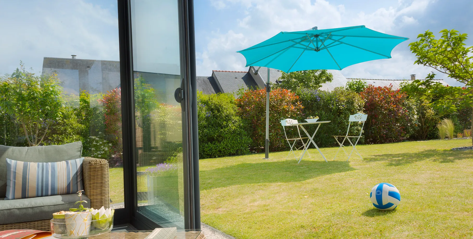 set tavolo e sedia all’ombra di un ombrellone decentrato fissato in una base discreta al centro del prato