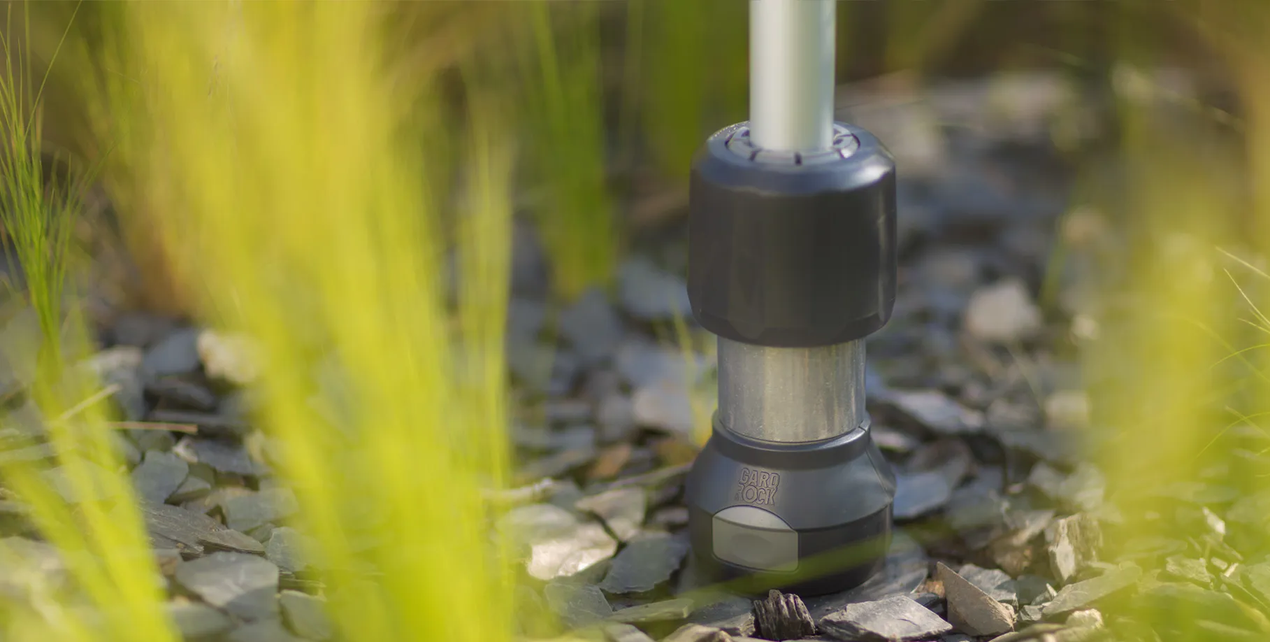 ombrellone inclinato fissato con sistema Gard&Rock in un giardino verde, coppia che conversa all’ombra