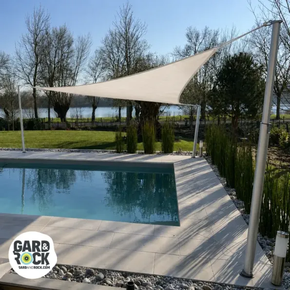 Vela ombreggiante tesa sopra una piscina, offre protezione solare e un’atmosfera elegante.